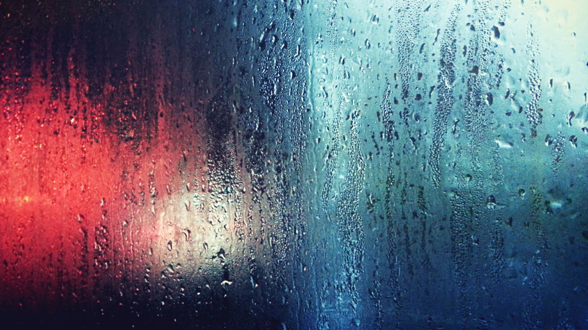 Blurred colors while looking through a foggy wet window.