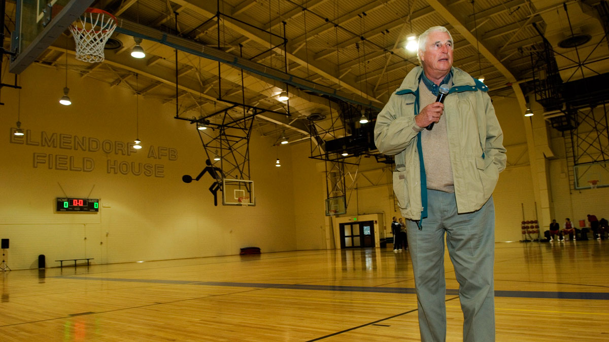 Bob Knight standing in a school gym talking to an audience.