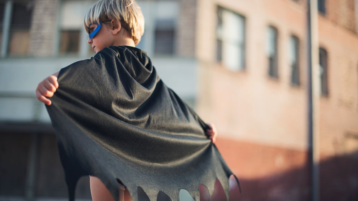 Kid wearing a superhero mask and cape.